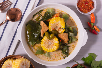 Sayur Lodeh is a vegetable dish made with coconut milk that is typical of Indonesia, especially in Central Java and DI Yogyakarta. Served in a bowl on a white table. Selective focus.
