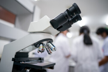 A group of people are standing around a microscope, looking at something