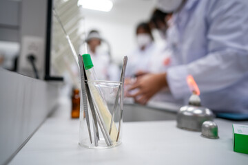 A group of people are working in a lab with a glass beaker on a table