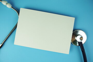 stethoscope with paper card top view on blue background, health and business concept