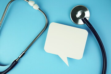 Stethoscope with speech bubble top view on blue background, health and business concept