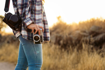 Unrecognizable woman taking photos with analog camera in the countryside