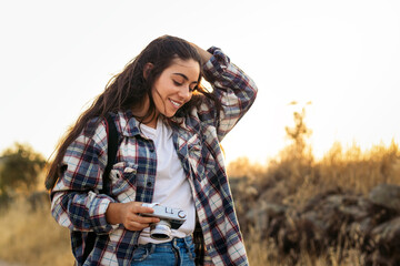 Young woman taking photos with analog camera in the field at sunset