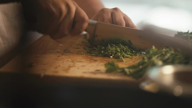 Chef cutting parsley on cutting board in kitchen