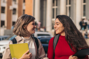 Two student girls looking each other and smiling. Leaving class