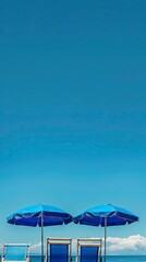 Fototapeta premium blue umbrella and sea facing chairs under Blue sky, Summer days in beach