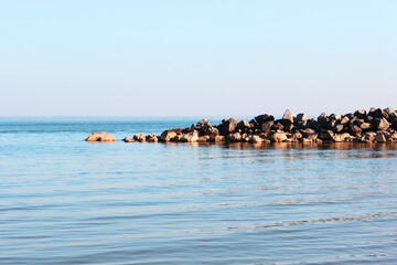 Blue sea and blue sky, beautiful waves. View from the beach to the rocky bay Morning light over the sea in Sanremo,