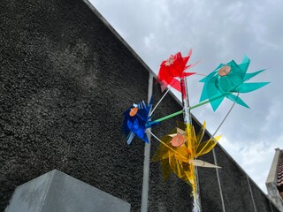 Colorful four windmill toys attached on a cross stick spinning in the wind under the sky