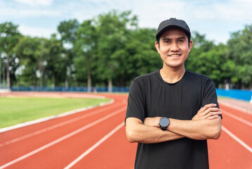 Portrait of a smiling young adult asian man wearing sportswear in running track. Happy handsome...