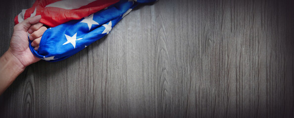 hand-holding an USA flag banner on a wooden table with copy space. Memorial Day or 4th of July