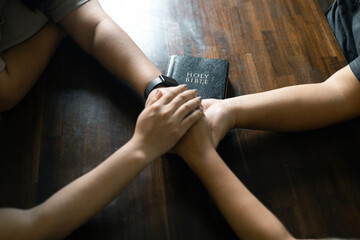 Woman gathered with her Christian friends in church, Bible close as they joined in prayer, feeling warmth of their religious family bond within group.