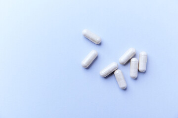 Creatine capsules on bright paper background. Soft focus. Close up. Copy space.	