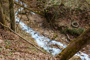 A ravine in which a blue stream flows after the illegal dumping of pollutants