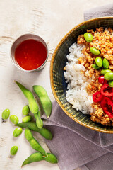 Vegan food. Soy meat, white rice, beans, red pepper on light wooden background