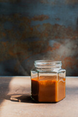 omemade caramel sauce in a glass jar on rustic table
