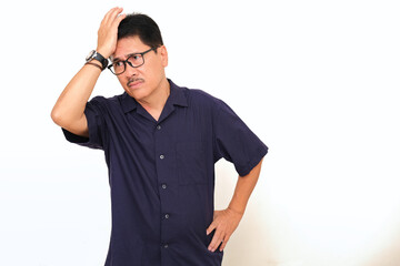 A middle-aged man  is standing with sad, confused expression; one hand supporting his head