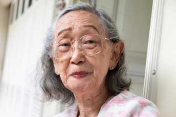 Beautiful healthy Southeast Asian elderly woman wearing eyeglasses smiling and looking at camera