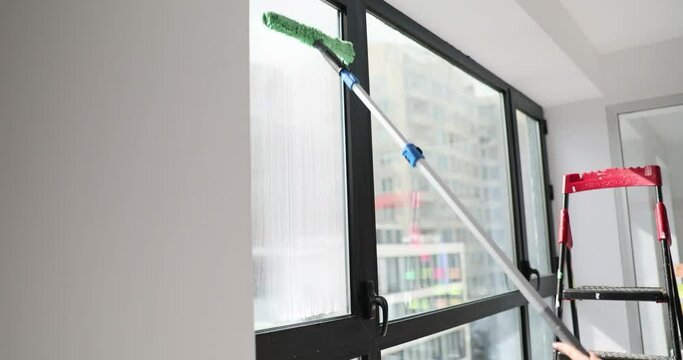 Housewife washes window with long brush