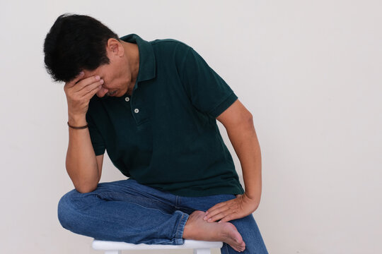 A man sitting on a stool; hand supporting his head