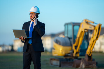 Architect at a construction site. Architect man in suit and helmet at construction site. Confident...
