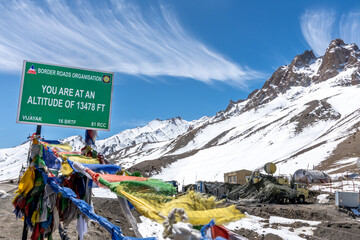 Green sign marking the summit of a high mountain pass in the northern Indian Himalayas near Leh