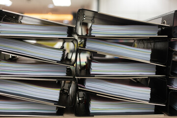 Files stacked on filing cabinet. A large pile of binders filled with papers. Overflowing with...
