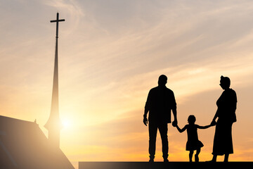 Silhouette of Family holding hands enjoying sunset with blurred the cross on the church