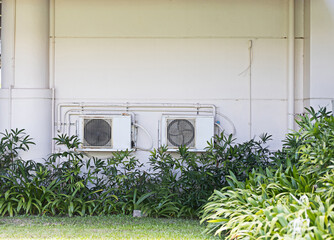 The cooling air conditioner is installed outside the building and surrounded by trees.