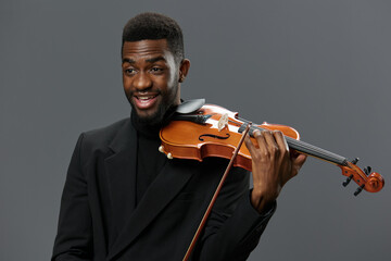 Professional African American musician in elegant suit holding a violin on a neutral gray background