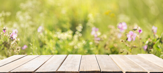 empty wooden table and summer meadow with wild flowers