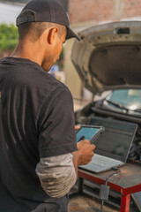 Mechanic using electronic device to repair a car
