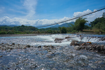 Sabahan hanging bridge over the Melangkap river with background of mountain range. Scene from Tegudon Tourism Village.