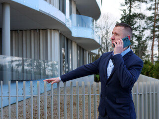 A Businessman engages in a phone conversation outside an office building, dressed in formal...