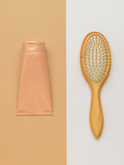 Massage comb and hair care product on a white and beige background.