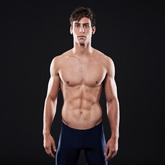 Fototapeta premium Man, studio and body portrait or confident athlete, workout and swimming training for health exercise. Wellness instructor, serious and male person in swimwear and isolated on black background