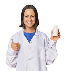 Young Caucasian female pharmacist with pills smiling and raising thumb up