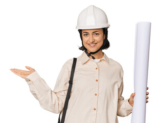 Young Caucasian female architect in studio showing a copy space on a palm and holding another hand on waist.