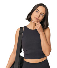 Young Caucasian sportswoman with backpack looking sideways with doubtful and skeptical expression.