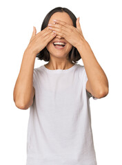 Young Caucasian woman with short hair covers eyes with hands, smiles broadly waiting for a surprise.