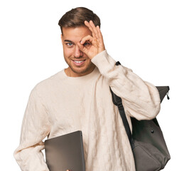 Young student man with a laptop excited keeping ok gesture on eye.