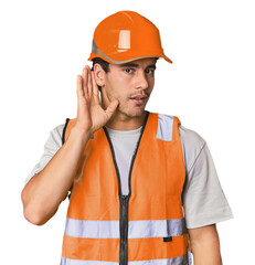 Young Hispanic worker in safety gear trying to listening a gossip.