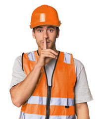 Young Hispanic worker in safety gear keeping a secret or asking for silence.