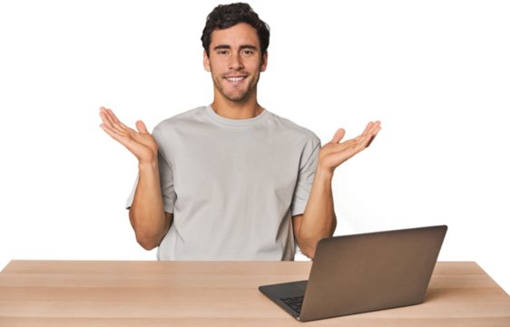 Hispanic young man working on laptop makes scale with arms, feels happy and confident.