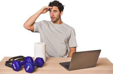 Hispanic trainer planning workout looking far away keeping hand on forehead.
