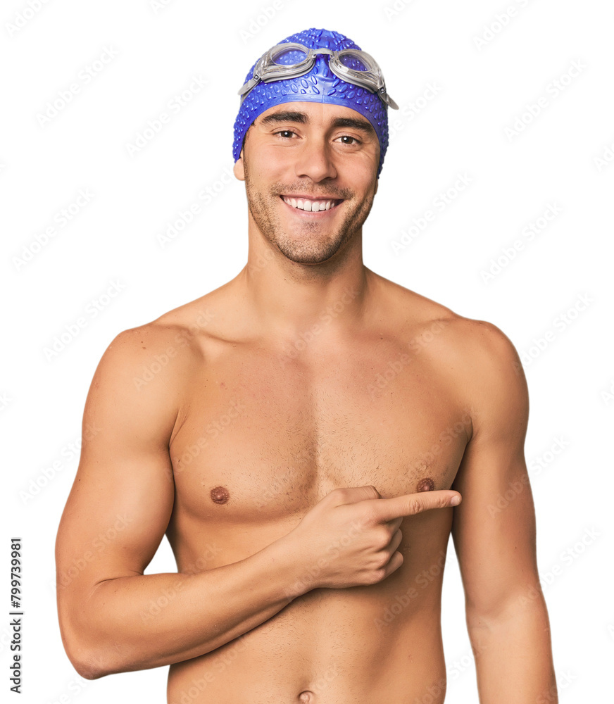 Wall mural Young Hispanic man with swim gear smiling and pointing aside, showing something at blank space.