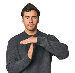 Young Hispanic man in studio showing a timeout gesture.