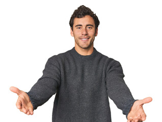Young Hispanic man in studio showing a welcome expression.