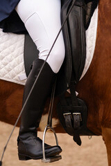 Equestrian leg in stirrup, riding attire, close-up.
