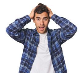 Young Hispanic man in studio screaming, very excited, passionate, satisfied with something.