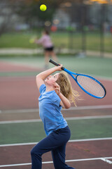 Preteen child swinging racket while training on tennis court at sport playground. Active exercise for kids. Summer activities for children. Child tennis player with racket learning to serve ball.